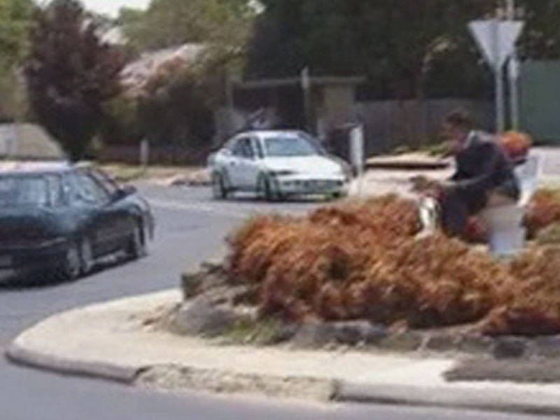 Homme en costard fait ses besoins sur rond point
